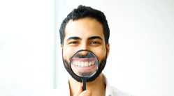 man holding magnifying glass to smile 