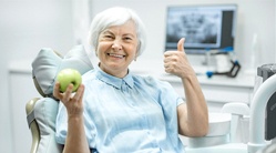 Woman smiling and giving thumbs up at dental office