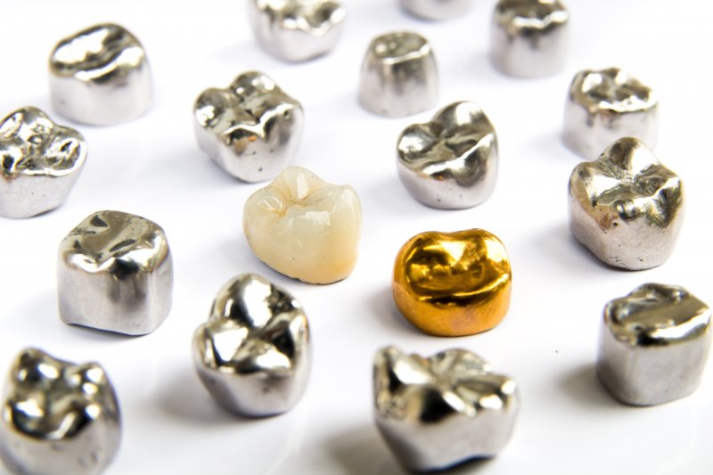 Dental crowns made of all kinds of materials, laid out on a table.