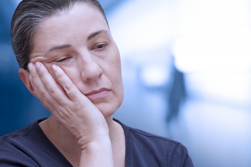 Woman holding her jaw due to TMJ pain